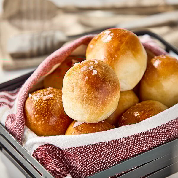 A basket filled with Pennant Parker House style white dinner rolls.