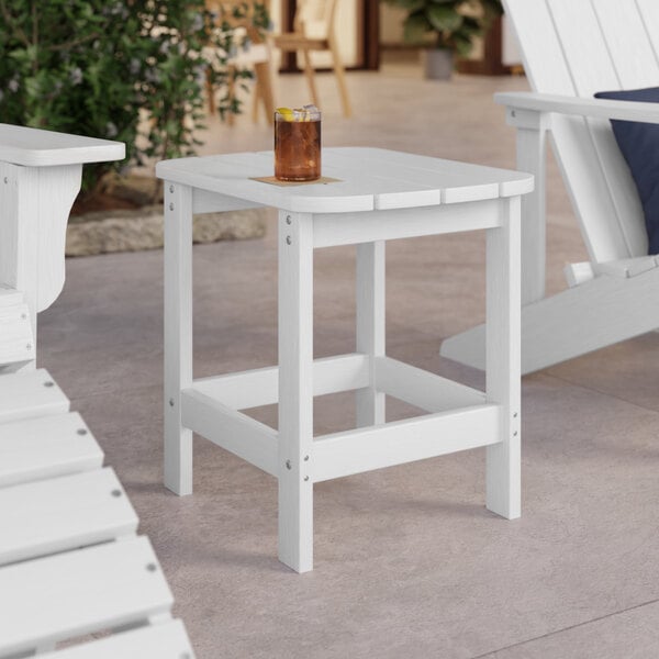 A white Lancaster Table & Seating Adirondack side table with a drink on it.