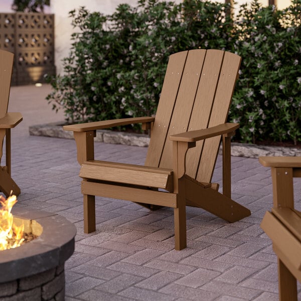 Two brown Lancaster Table & Seating Adirondack chairs on a brick patio.