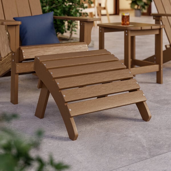 A brown Lancaster Table & Seating Adirondack footrest on a patio.