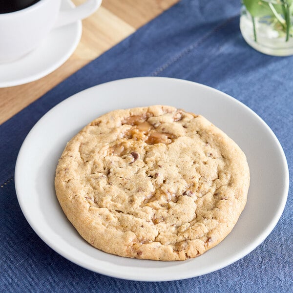 David's Cookies Decadent Salted Caramel cookie on a plate next to a white cup of coffee.