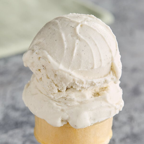 A scoop of G.S. Gelato Tahitian Vanilla Bean Gelato in a white ice cream cone.