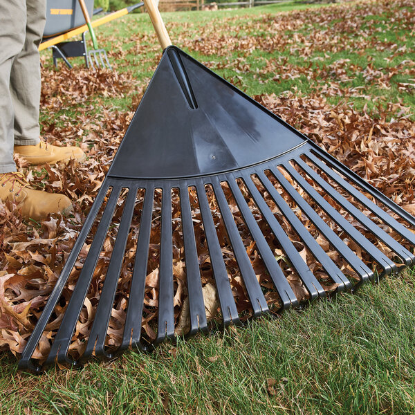 A True Temper poly leaf rake with a hardwood and steel handle and cushion grip being used to rake leaves.