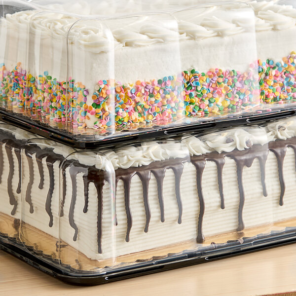 A Baker's Lane cake with white frosting and sprinkles in a plastic container.