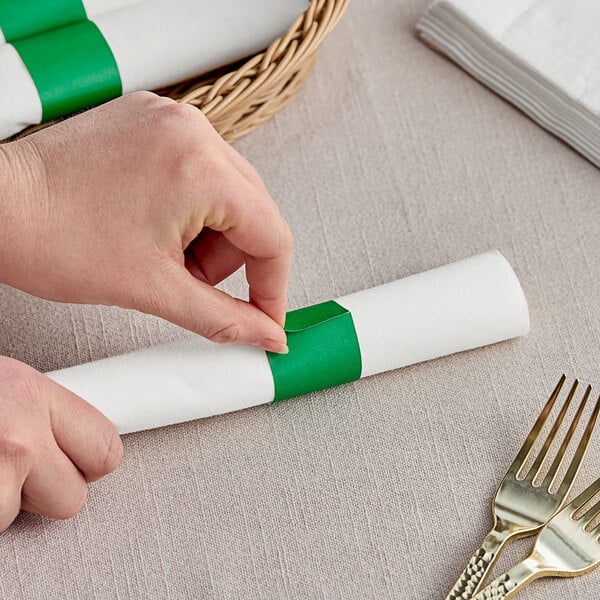 A hand rolling a green Choice paper napkin band around a napkin.