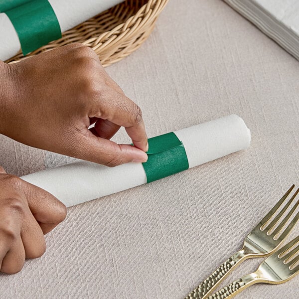 A person's hands wrapping a napkin with a green Choice paper band.