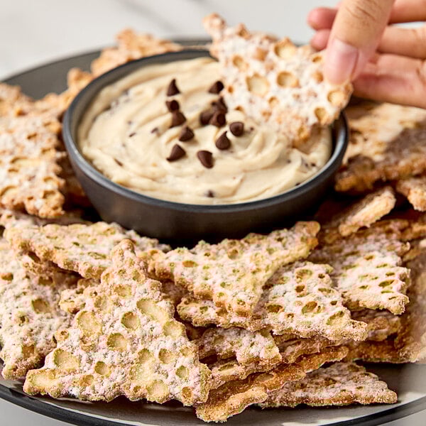 A plate of Seviroli Sugar-Dusted Cannoli Chips with a bowl of chocolate chips on it.