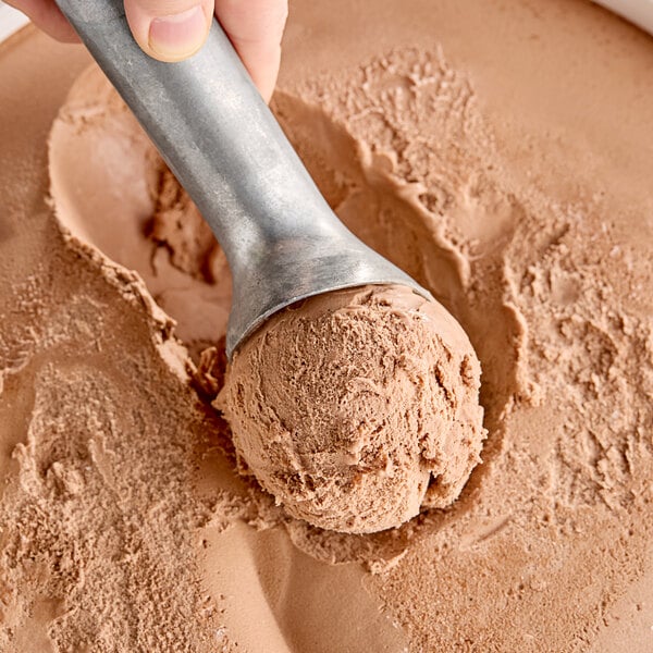 A hand scooping Klein's vegan chocolate ice cream into a bowl.