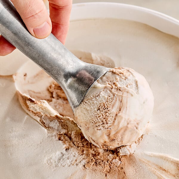 A hand scooping Klein's Real Kosher Vegan Vanilla Fudge Ice Cream with a metal scoop.