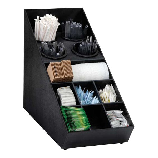 A black Dispense-Rite countertop organizer with different types of condiments, straws, and sugar packets inside.