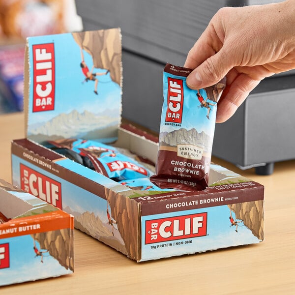 A hand holding a package of Clif Bar chocolate brownie energy bars.
