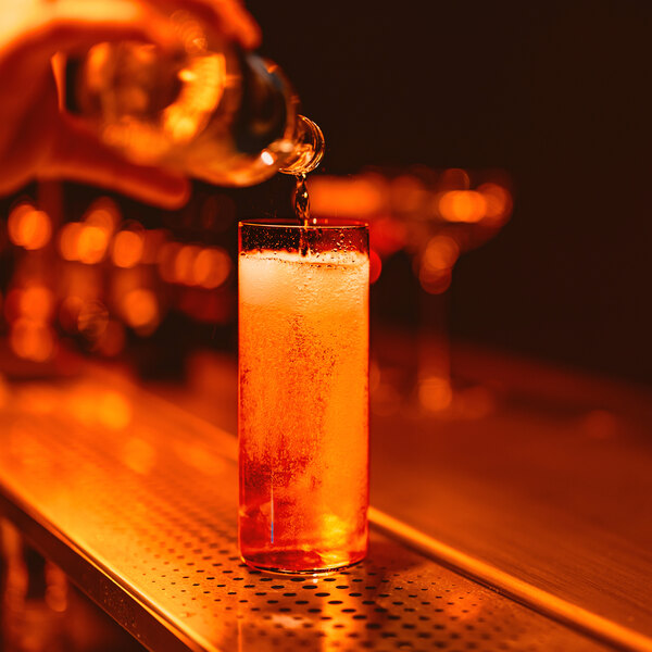 A bartender pouring a drink into a Stolzle Kyoto long drink glass.