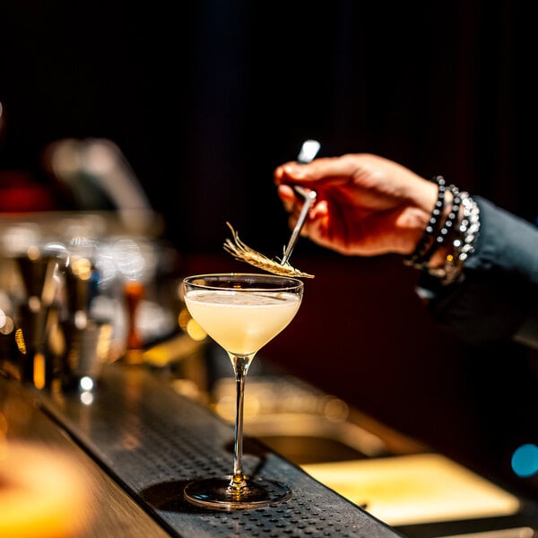 A bartender pouring a cocktail into a Stolzle Kyoto Nick and Nora glass.