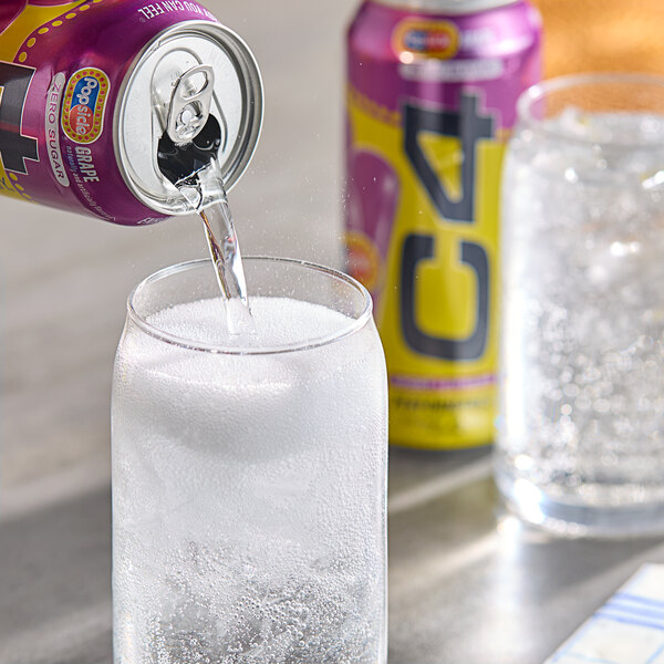 A C4 Energy Grape Popsicle can pouring a drink into a glass filled with ice.