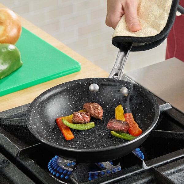 A person cooking food in a Nordic Ware frying pan on a stove.