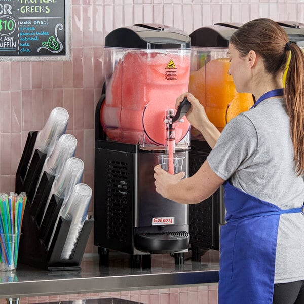 A commercial single-tank frozen beverage machine dispensing a red slushy drink into a clear cup.