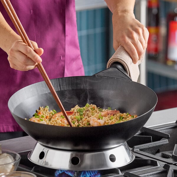 A 14-inch oxidized carbon steel Mandarin wok being used to cook stir-fried rice on a stovetop.