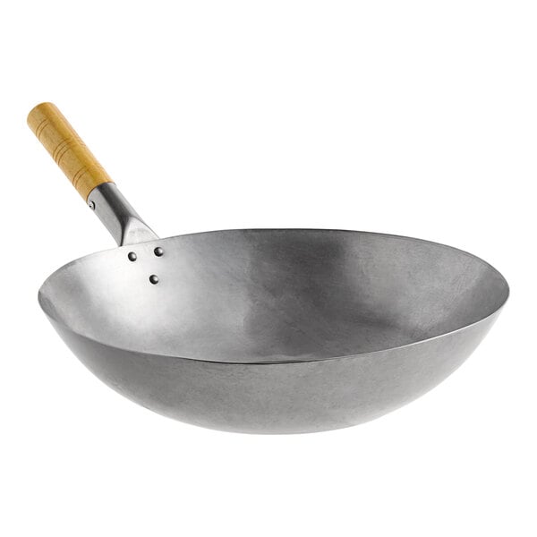 A large carbon steel flat bottom wok with a wooden handle.
