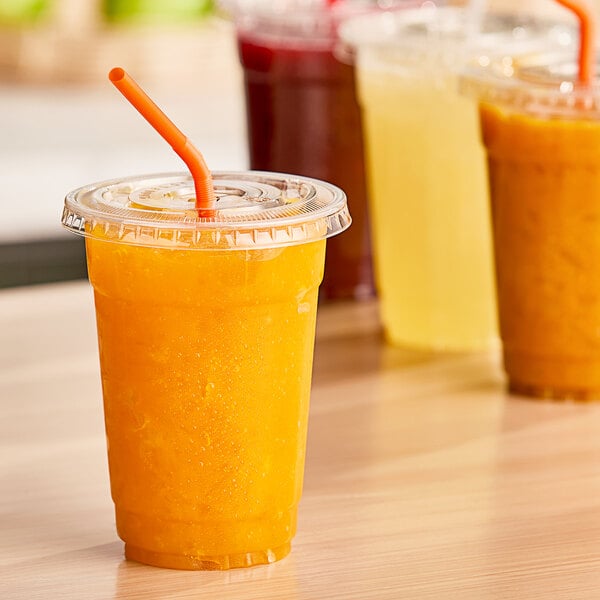 A row of plastic cups filled with mango passion juice with straws.