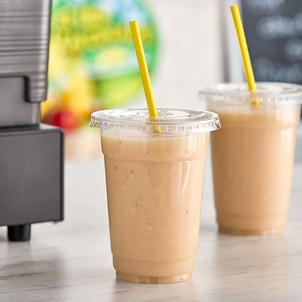 A plastic cup with Fresh Blends Banana Beverage Base for FreshBlender in it with a straw, next to another cup with a drink in it.