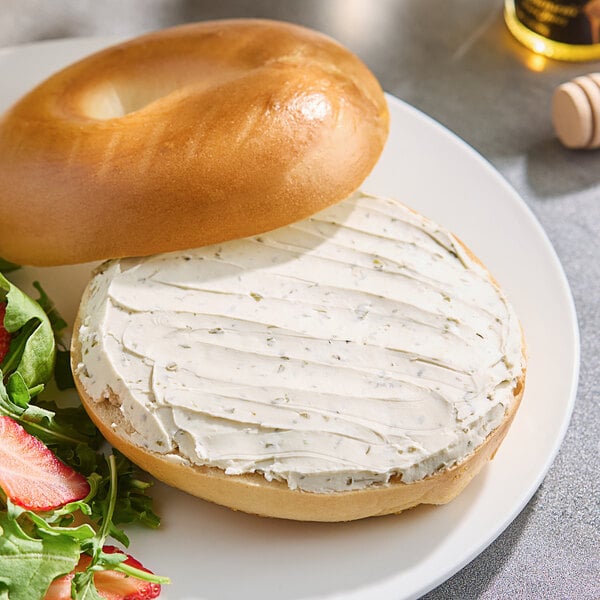 A bagel with Stockeld Dreamery spring scallion cream cheese on a plate.