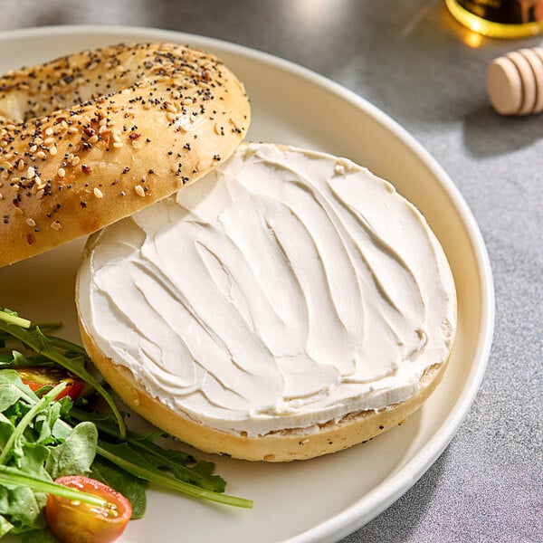 A bagel with Stockeld Dreamery plant-based cream cheese and salad on a plate.