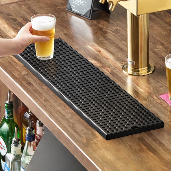 A rectangular black matte surface-mount beer drip tray on a wooden bar counter.