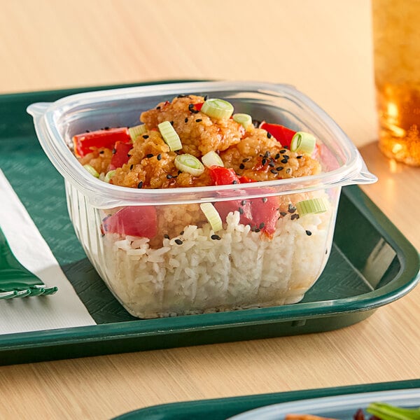 A Dart clear polypropylene square bowl filled with food on a white tray.