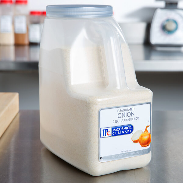 A plastic container of McCormick Culinary Granulated Onion powder on a counter.
