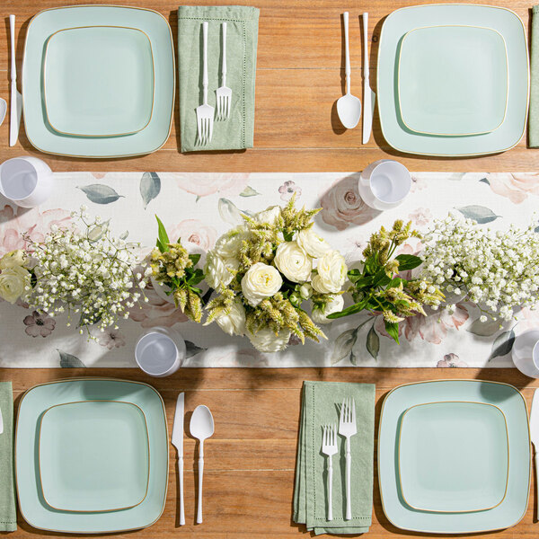 A Posh Setting turquoise plastic coupe plate with gold band on a table with plates and cutlery.