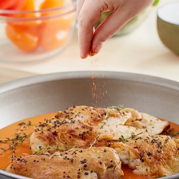 A person sprinkling Cholula Chili Lime seasoning on food.