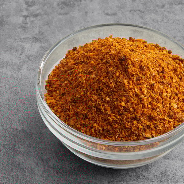 A bowl of McCormick Grill Mates Fiery Habanero and Roasted Garlic seasoning with ground orange powder.