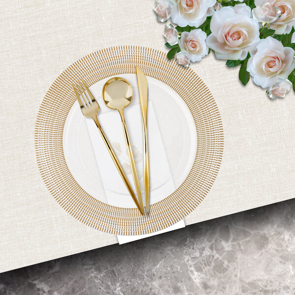 A Posh Setting clear charger plate with a gold textured wide rim and a gold fork and knife on it.