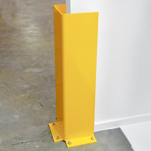 A yellow steel gantry or jib guard installed at the corner of a wall for protection.