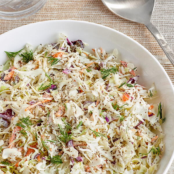 A bowl of coleslaw with carrots and celery on a white background.