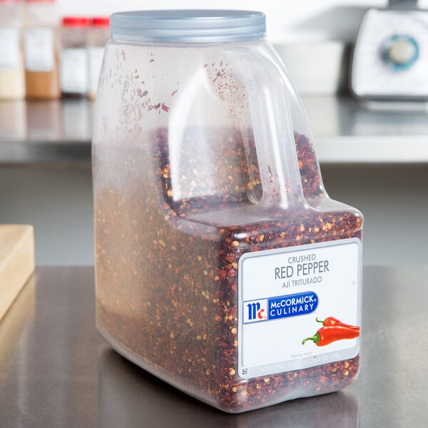 A case of three large McCormick Culinary crushed red pepper containers on a counter.