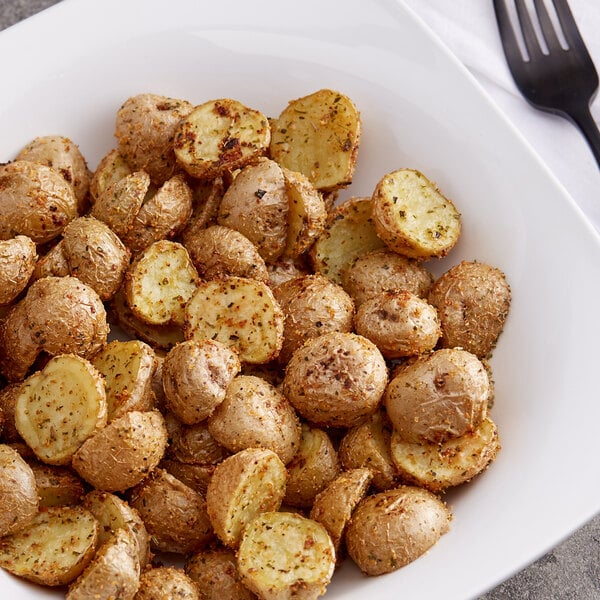 A plate of roasted potatoes seasoned with Lawry's Salt-Free Garlic and Herb Seasoning with a fork on the side.