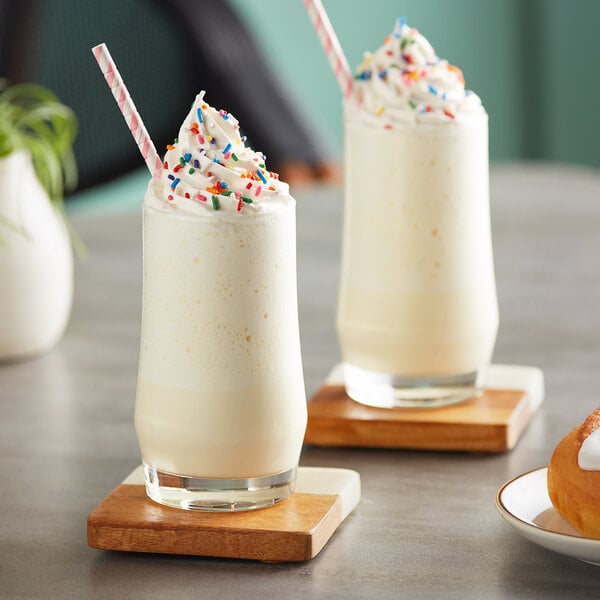 Two glasses of white cake batter frappes with sprinkles.