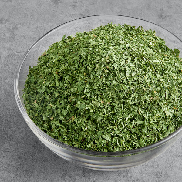 A bowl of McCormick Culinary parsley flakes on a gray surface.