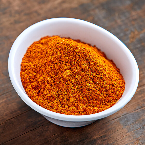 A bowl of orange powder on a wooden table.