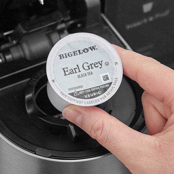 A hand holding a white round container with black text.