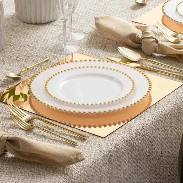 A table set with gold Posh Setting mirrored charger plates and gold utensils.