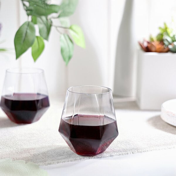 A clear plastic stemless diamond-shaped wine glass filled with red wine.