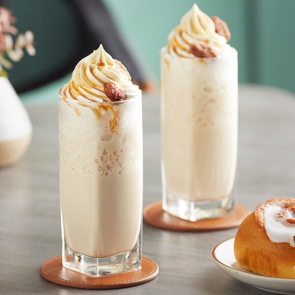 Two glasses of Big Train Dulce de Leche blended ice coffee with whipped cream and a pastry.