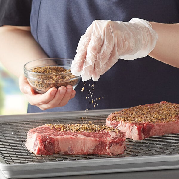 A piece of steak being seasoned with McCormick Montreal Steak Seasoning.