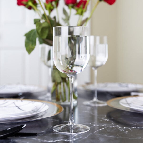 A Posh Setting clear plastic wine goblet filled with red wine on a table in a restaurant dining area.