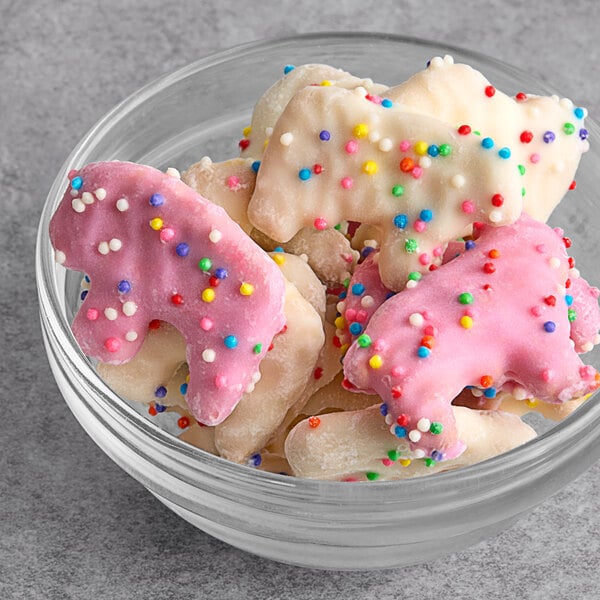 A bowl of pink and white yogurt-covered animal shaped cookies with sprinkles.