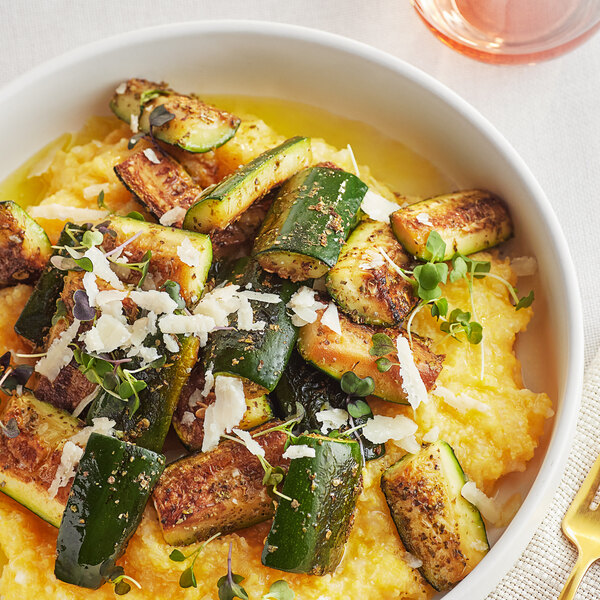 A bowl of zucchini and squash with McCormick Culinary Marjoram Leaves on a table.
