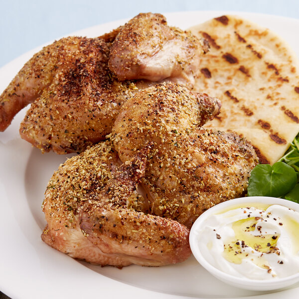 A plate of chicken topped with Lawry's Garlic, Rosemary, and Lemon Rub with a bowl of white sauce.