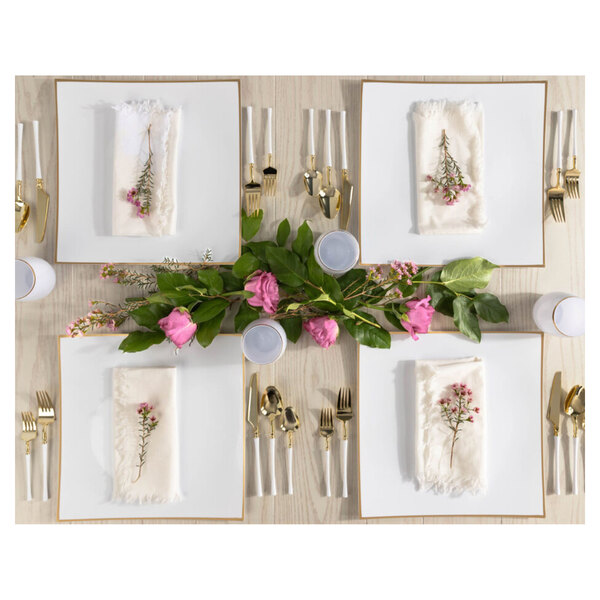 A table set with Posh Setting white plastic charger plates with gold rims, gold forks, and pink roses.